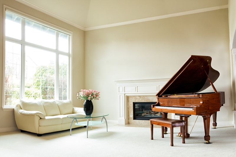 Clean white room with a white sofa to the left and a brown wooden piano to the right.